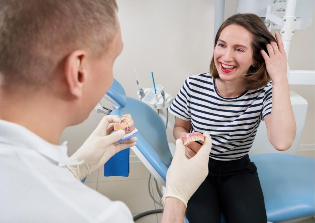 Dentist discussing porcelain implant options with a patient using a dental model during a treatment consultation.