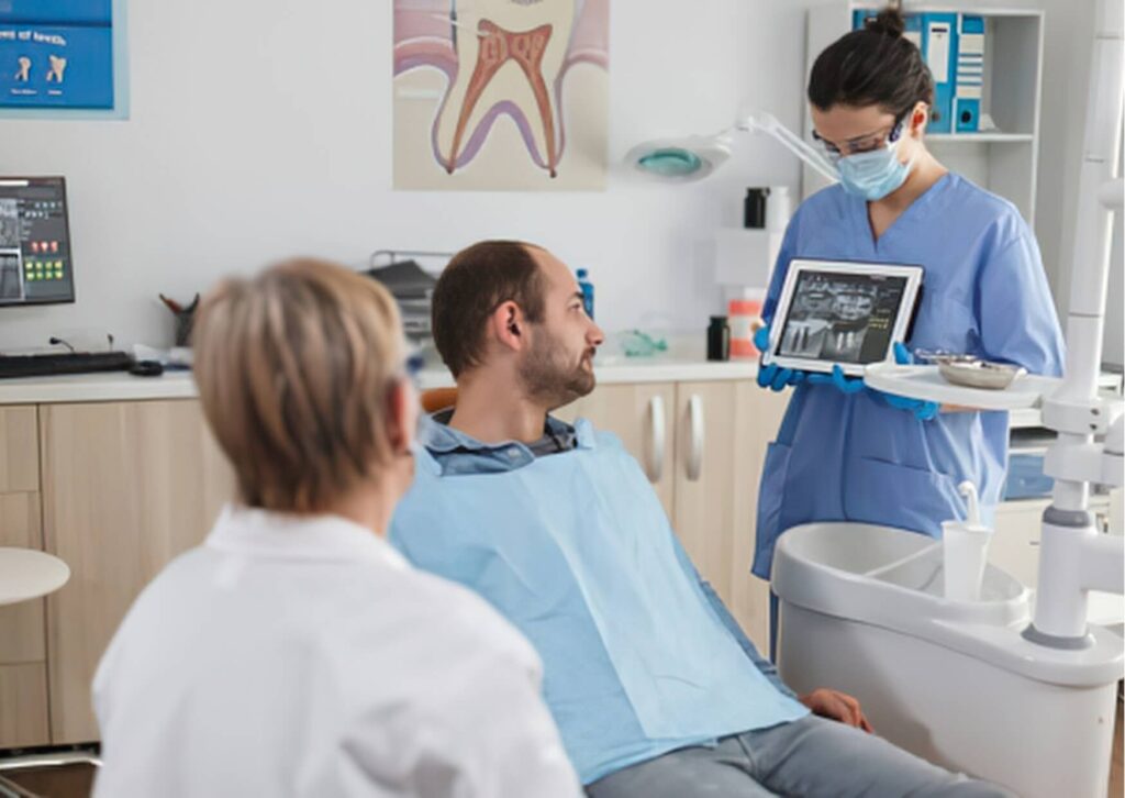 Dental team reviewing jaw X-rays with a patient to check for the need for bone grafting before dental implant surgery.