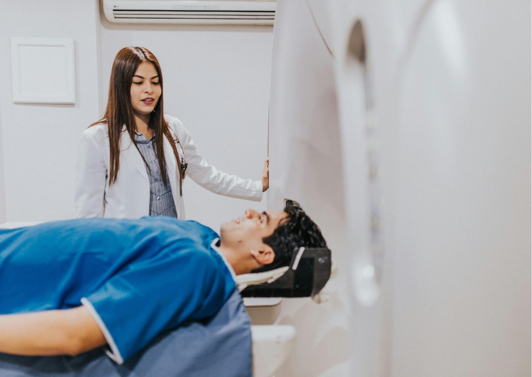 Patient preparing for an MRI scan while healthcare staff review medical history, including existing dental implants.